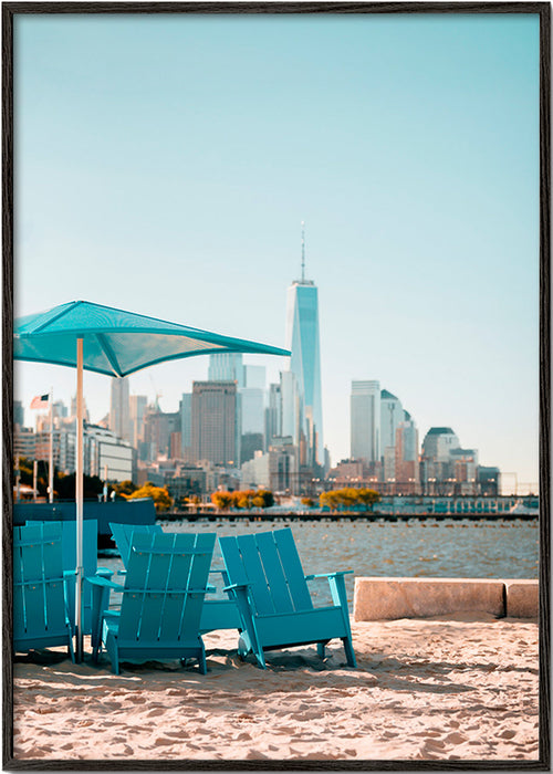 Poster di viaggio con sedie turchesi in spiaggia e skyline cittadino – Black Frame