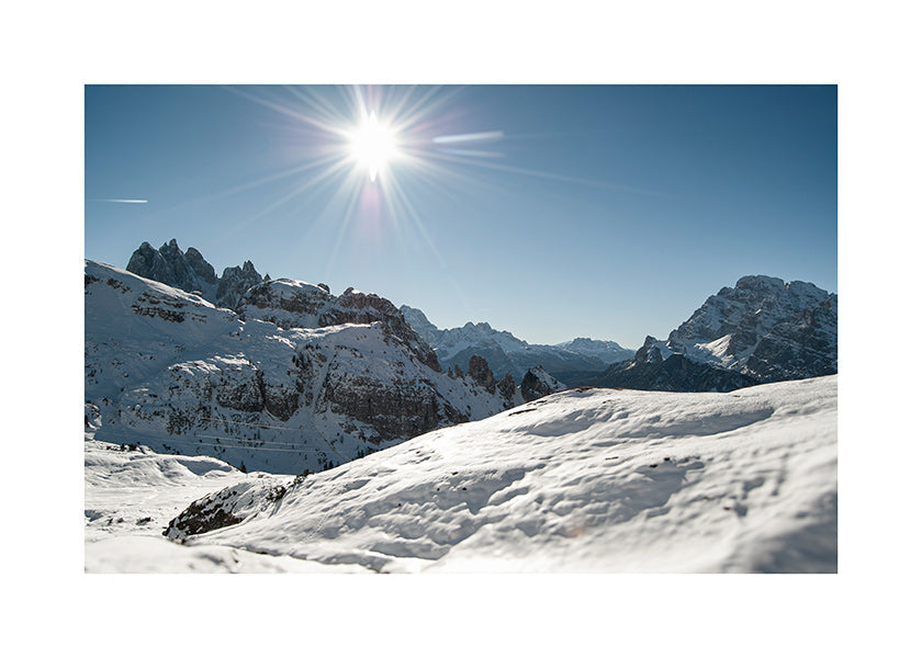 Arte paesaggistica: catena montuosa innevata con sole vivo