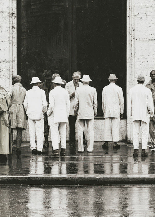 Fotografia in bianco e nero di uomini di spalle sotto la pioggia
